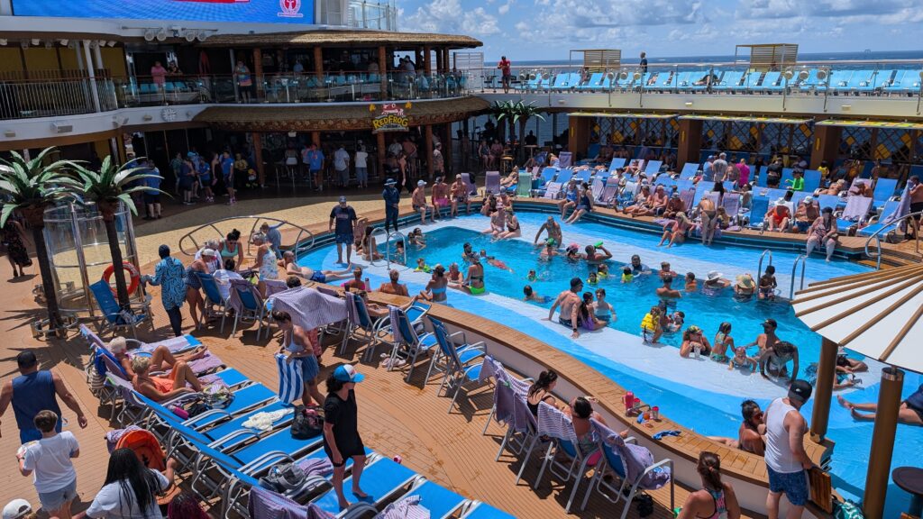 The main pool area on the Carnival Jubilee Lido Deck, featuring the BlueIguana Tequila Bar and plenty of lounge seating under a bright sky.