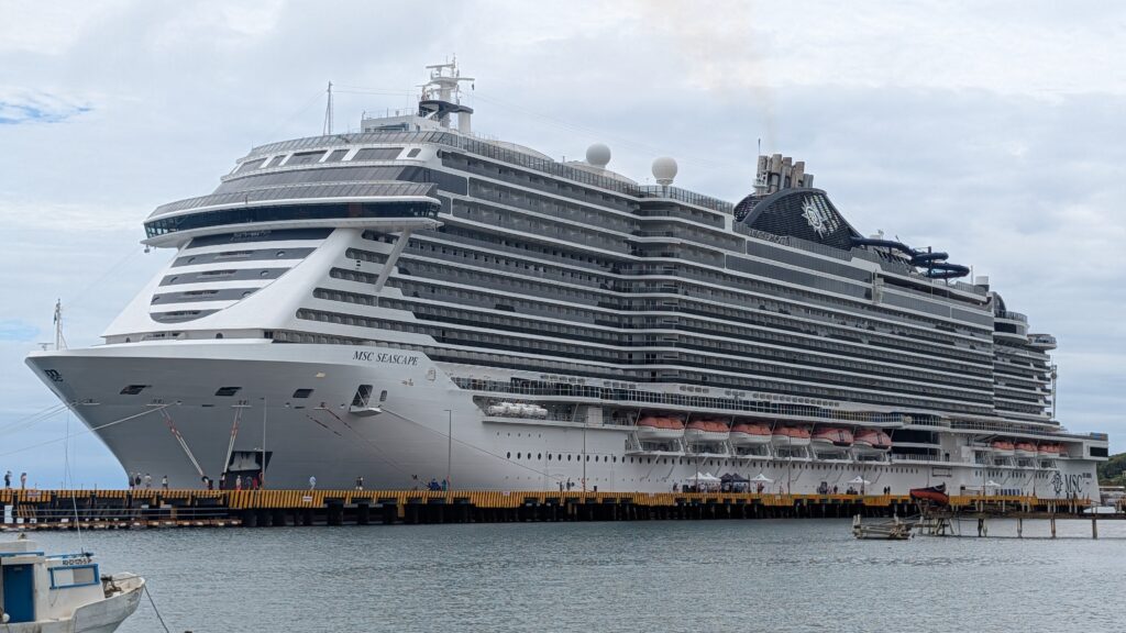 he MSC Seascape cruise ship docked at the Coxen Hole cruise terminal in Roatan, Honduras, under a clear blue sky.