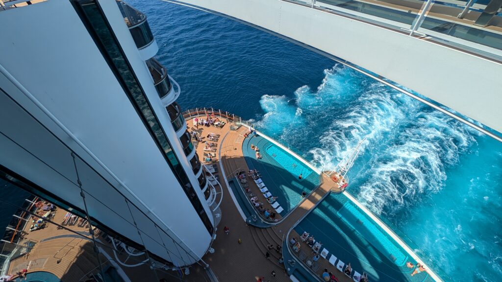 View looking down from the Bridge of Sighs on MSC Seascape, showing the Infinity Pool, ocean wake, and aft deck areas during a Caribbean cruise.