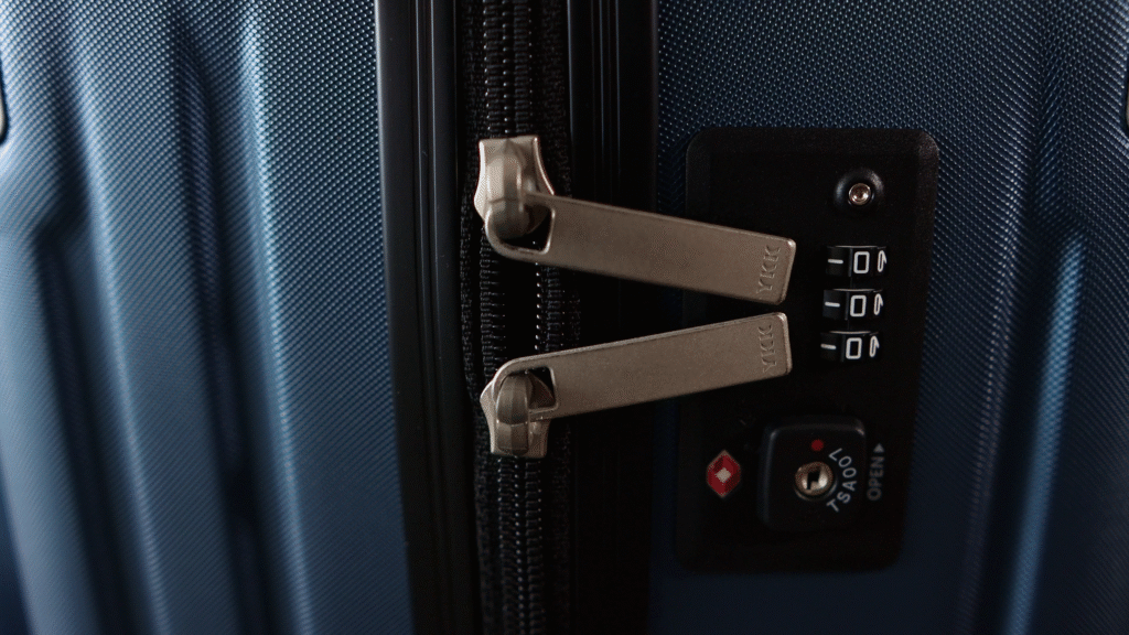 Close-up of the built-in TSA-approved combination lock and YKK zipper pulls on a navy Level8 Grace suitcase, highlighting the luggage's security and premium hardware features.