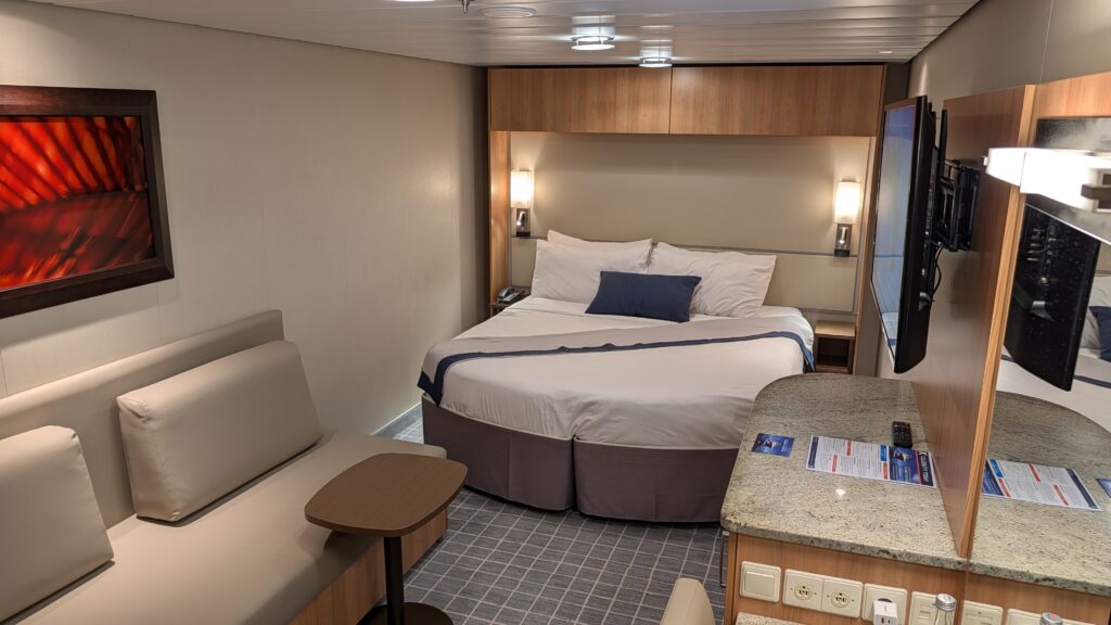 Celebrity Solstice Inside Stateroom 7160 showing the king bed, couch, vanity, TV, and sideways cabin layout.