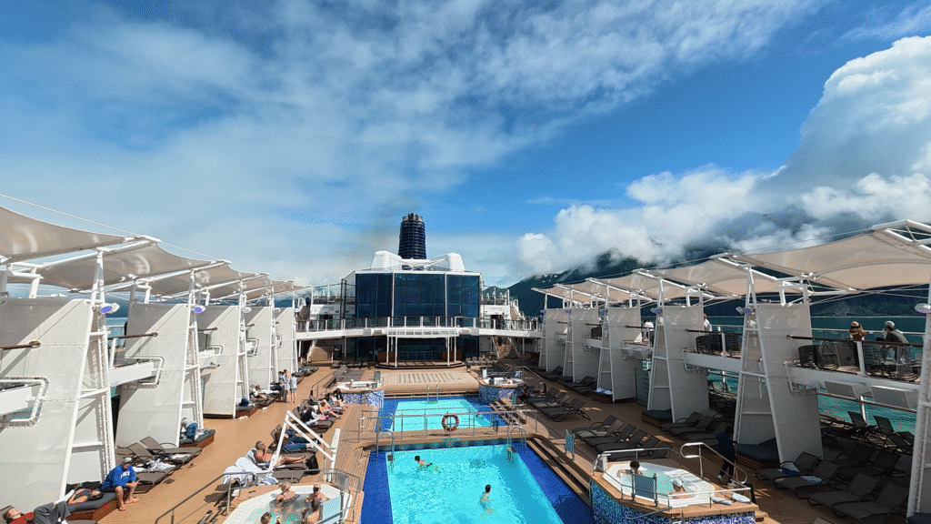 Celebrity Solstice Resort Deck featuring the main pool, hot tubs, lounge chairs, and Alaska scenery.