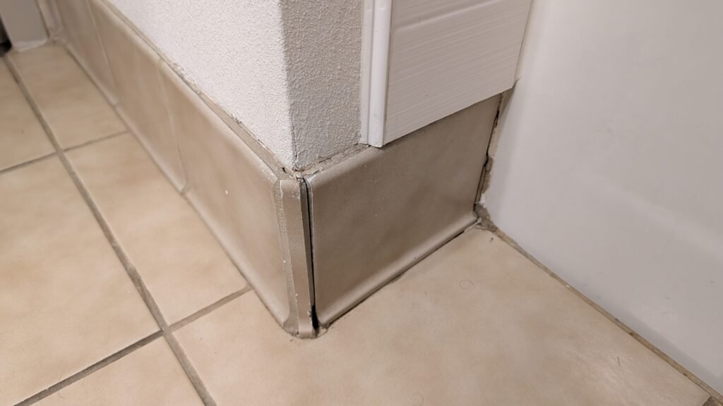 Aged bathroom floor tile and trim in the King Suite at the Country Inn & Suites by Radisson Seattle-Bothell.