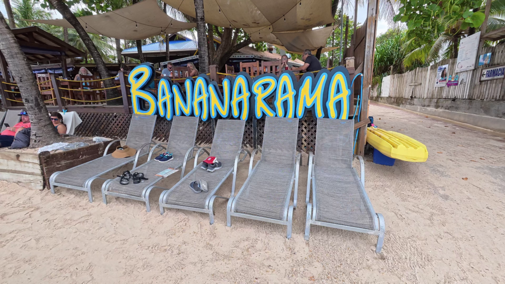 Beach loungers lined up in front of the Bananarama Beach Resort sign on West Bay Beach in Roatan, Honduras.