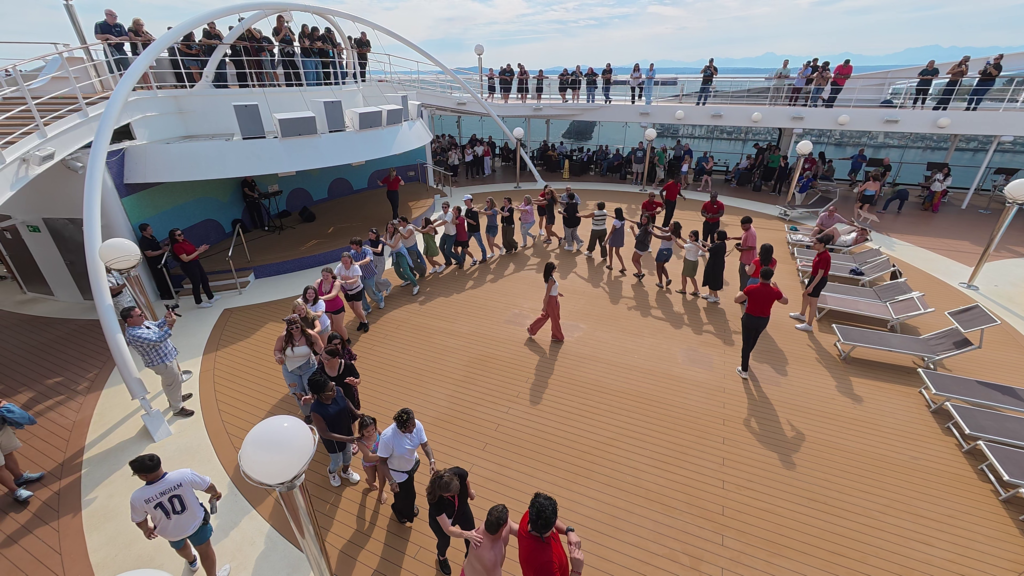 Passengers dancing during the MSC Poesia sail away party on the outdoor pool deck.