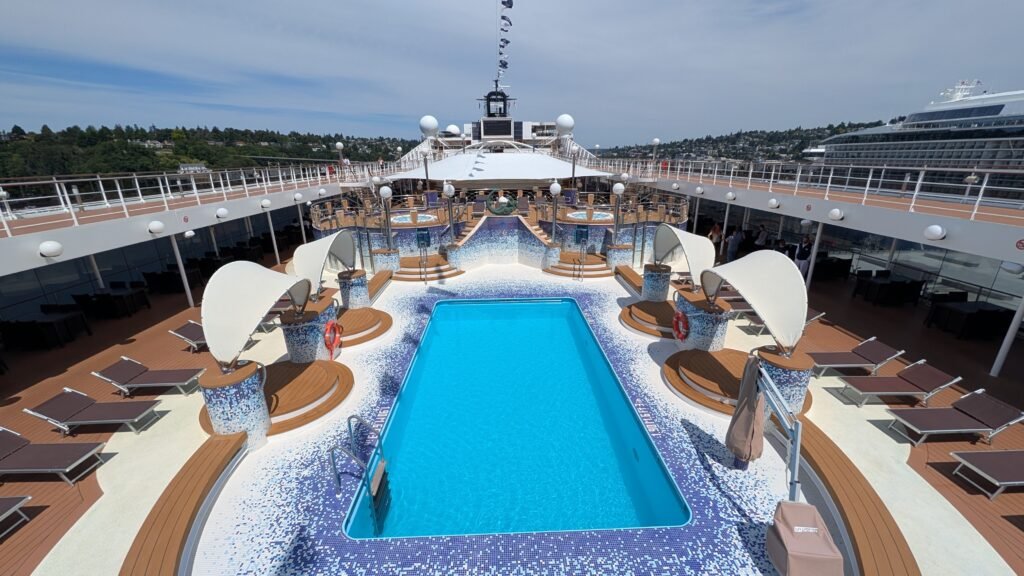 MSC Poesia pool deck with an outdoor swimming pool, raised hot tubs, and loungers.