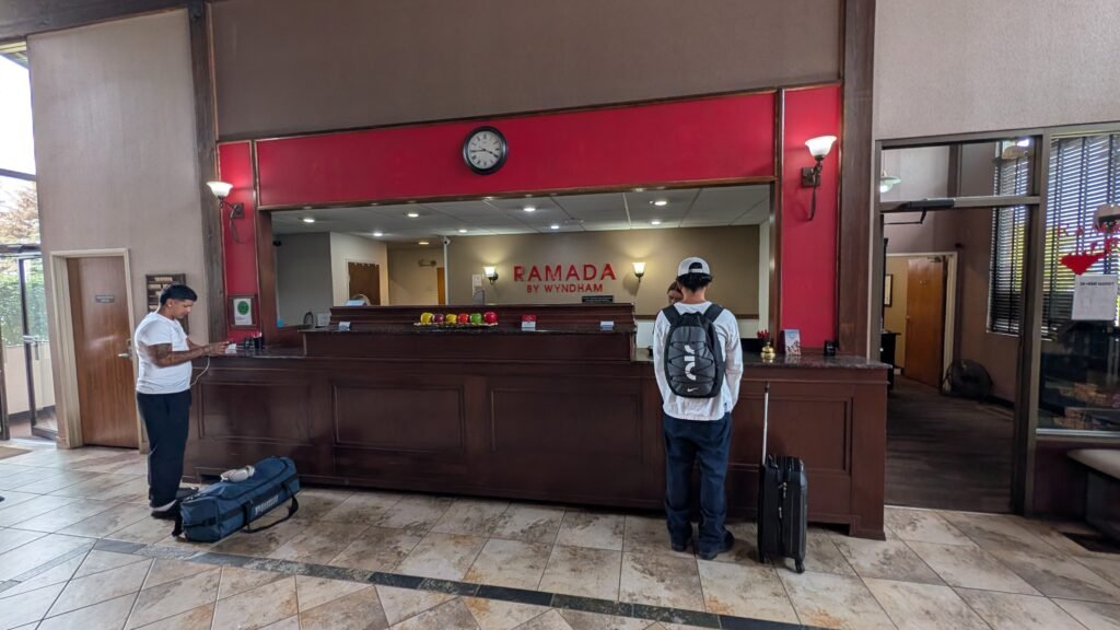 Ramada by Wyndham Spokane Airport lobby and front desk with dark wood reception counter and red accent wall.