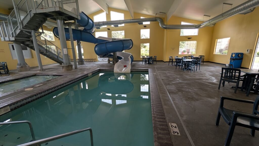 Indoor swimming pool and large blue waterslide at Ramada by Wyndham Spokane Airport in Spokane, Washington.