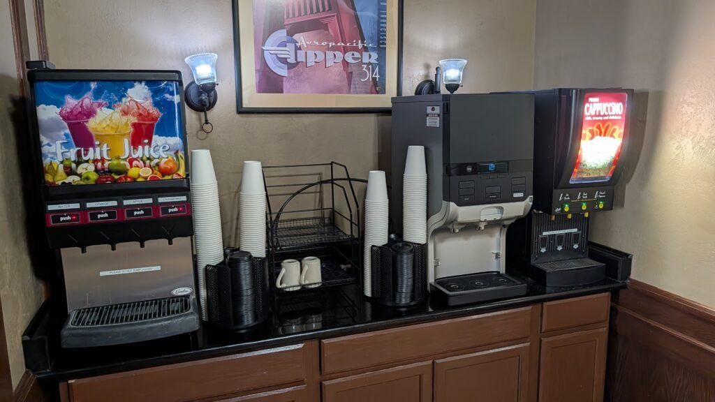 Breakfast beverage station with juice, coffee, and cappuccino machines at Ramada by Wyndham Spokane Airport.