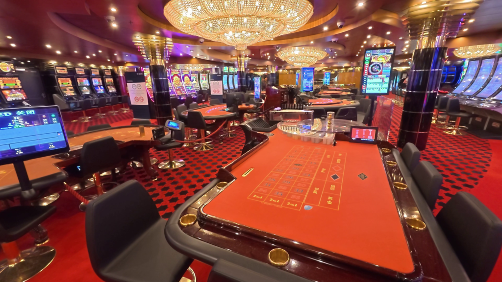 Casino Royal on the MSC Poesia showing roulette tables, slot machines, and chandeliers.