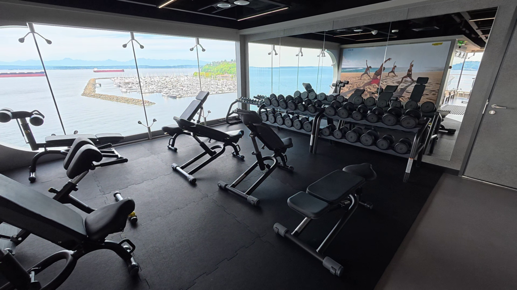 MSC Poesia fitness center with dumbbell racks, weight benches, and ocean views on Deck 14.